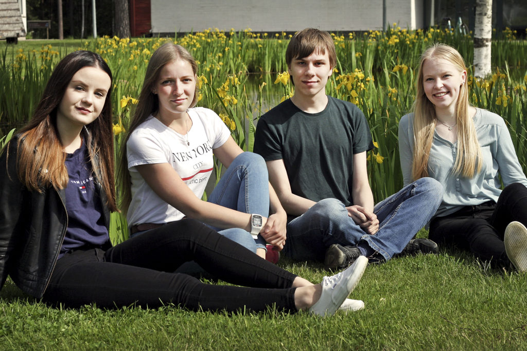 Veera Suokas, Marika Udelius, Tero Lepola ja Lotta Järvi istumassa opiston lammen rannalla.